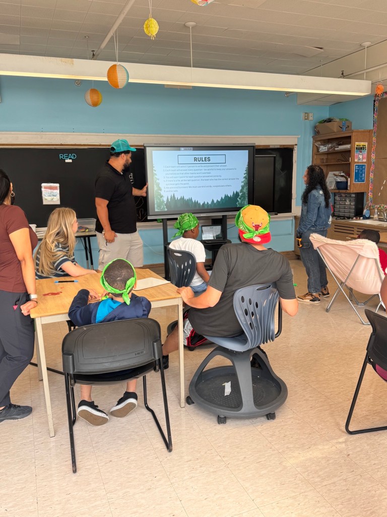 Los alumnos y el personal repasan las reglas de una actividad de trabajo en equipo inspirada en el programa «Survivor» en el colegio High Road.