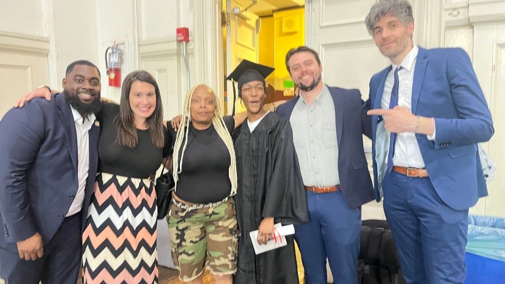 Un graduado del programa High Road de Ferguson posa con sus seguidores y el personal tras la ceremonia de graduación de 2026.