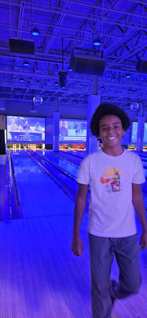 Sierra Gilbert student smiles beside the bowling lanes during a Fun Friday community outing.