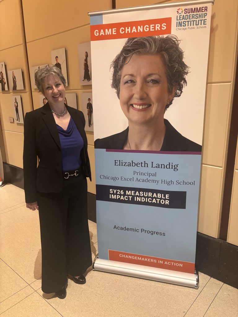 Elizabeth Landig stands beside her 2026 CPS Game Changer display recognizing academic progress at Chicago Excel Academy High School.