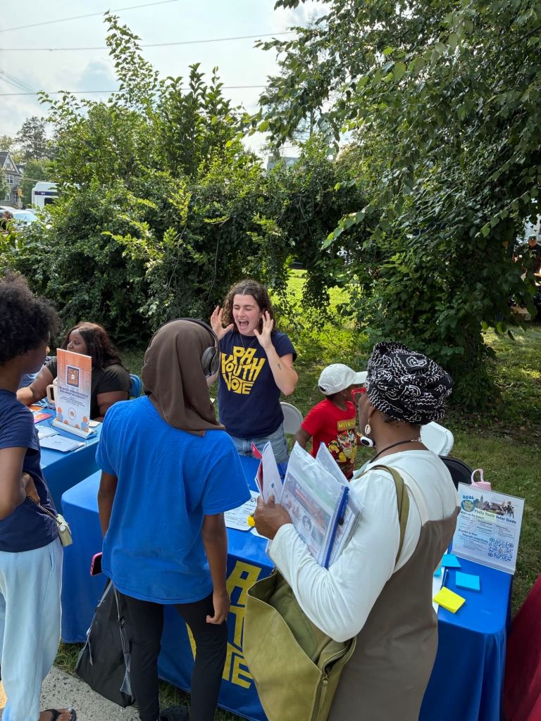 Families speak with community organizations at an outdoor resource table during the Philadelphia back-to-school event.