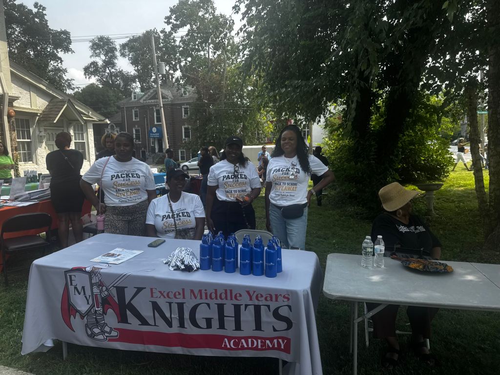 Excel Middle Years Academy staff stand behind their school information table at the Philadelphia back-to-school event.