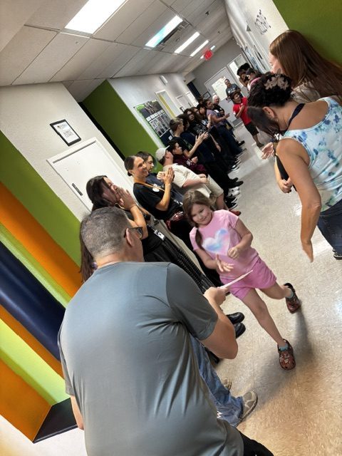 A young Sierra Gilbert student walks through a hallway lined with staff and classmates celebrating students recognized for respect.