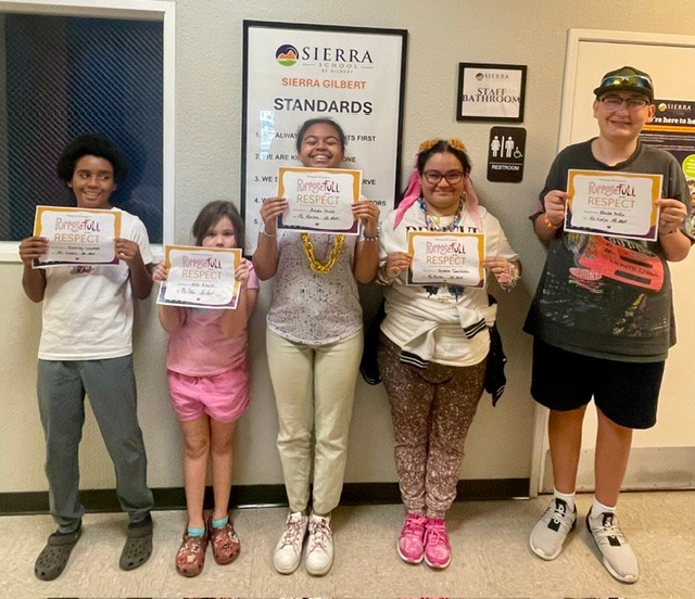 Five Sierra Gilbert students stand together holding Respect recognition certificates as part of the school’s character education program.