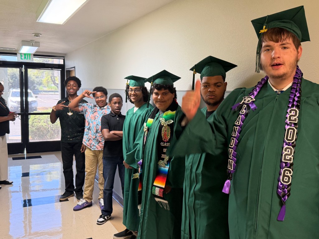Los alumnos de la Sierra School del condado de Solano se reúnen con los graduados de 2026, que llevan togas y birretes verdes.