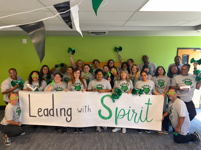 El personal de la Sierra School del condado de Solano se reúne detrás de una pancarta con el lema «Leading with Spirit» durante los preparativos para el nuevo curso escolar.