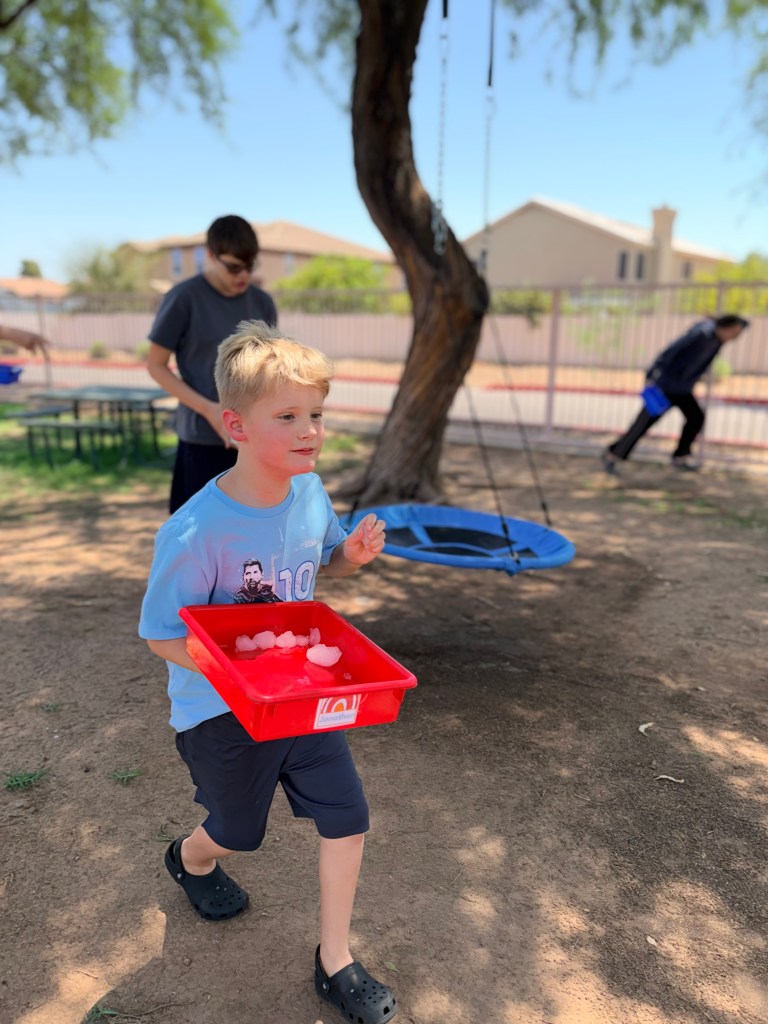 Sierra School of Gilbert student carries a tray of snowballs during an outdoor Fun Friday activity.