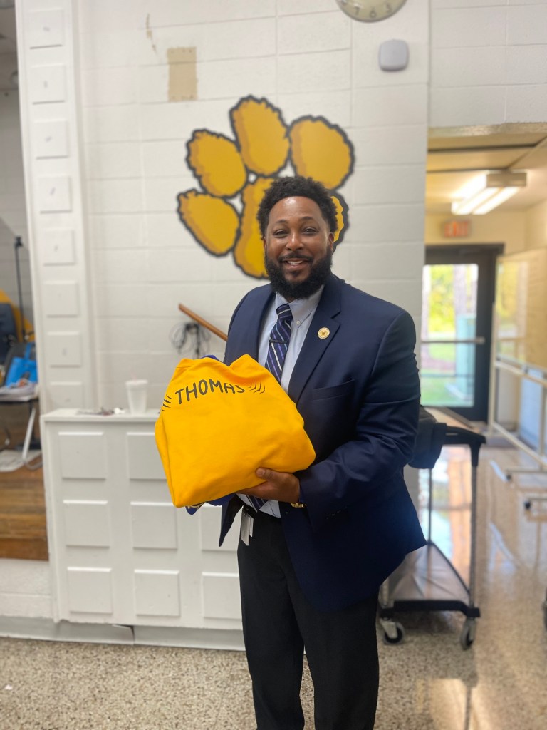 Royce Thomas sostiene un jersey dorado personalizado durante la ceremonia de reconocimiento a los socios del distrito de la Escuela de Estudiantes Destacados de la ciudad de Valdosta.
