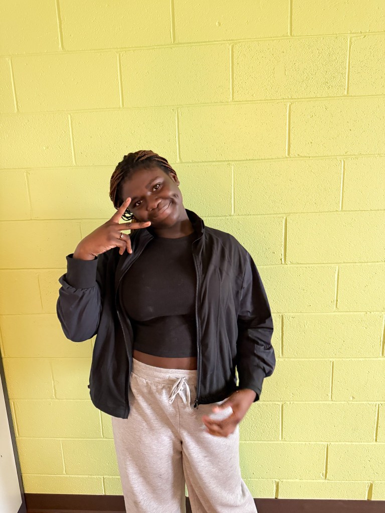 Aniyah, a student at High Road School of Bucks County, smiling and posing against a yellow wall.