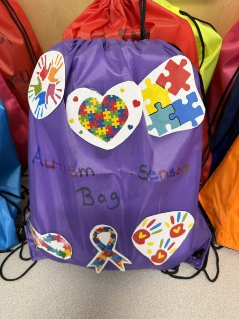 Purple sensory bag decorated with autism awareness symbols and colorful handprint designs at B.E.S.T. Academy.