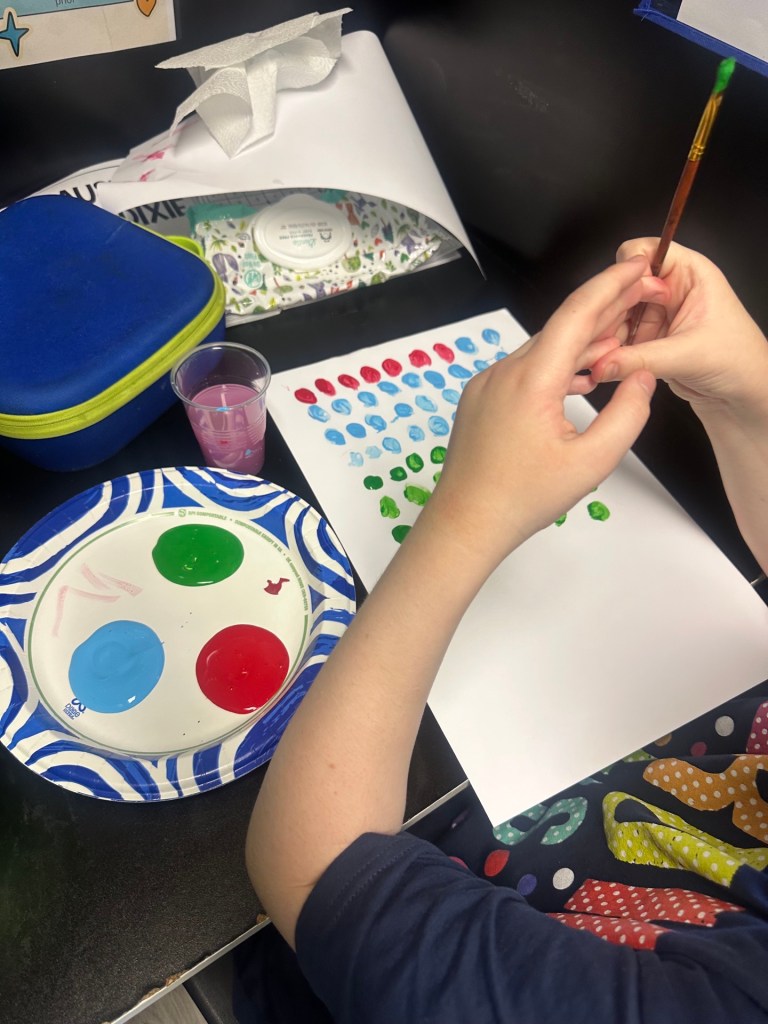 Un alumno pinta puntos de colores durante una actividad artística con motivo del Día Internacional del Punto en las escuelas High Road de Connecticut.