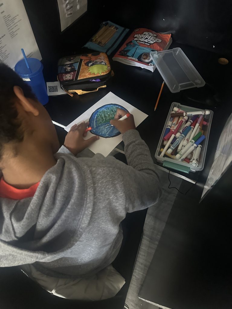 Student uses markers to create a colorful dot design for an International Dot Day art activity.
