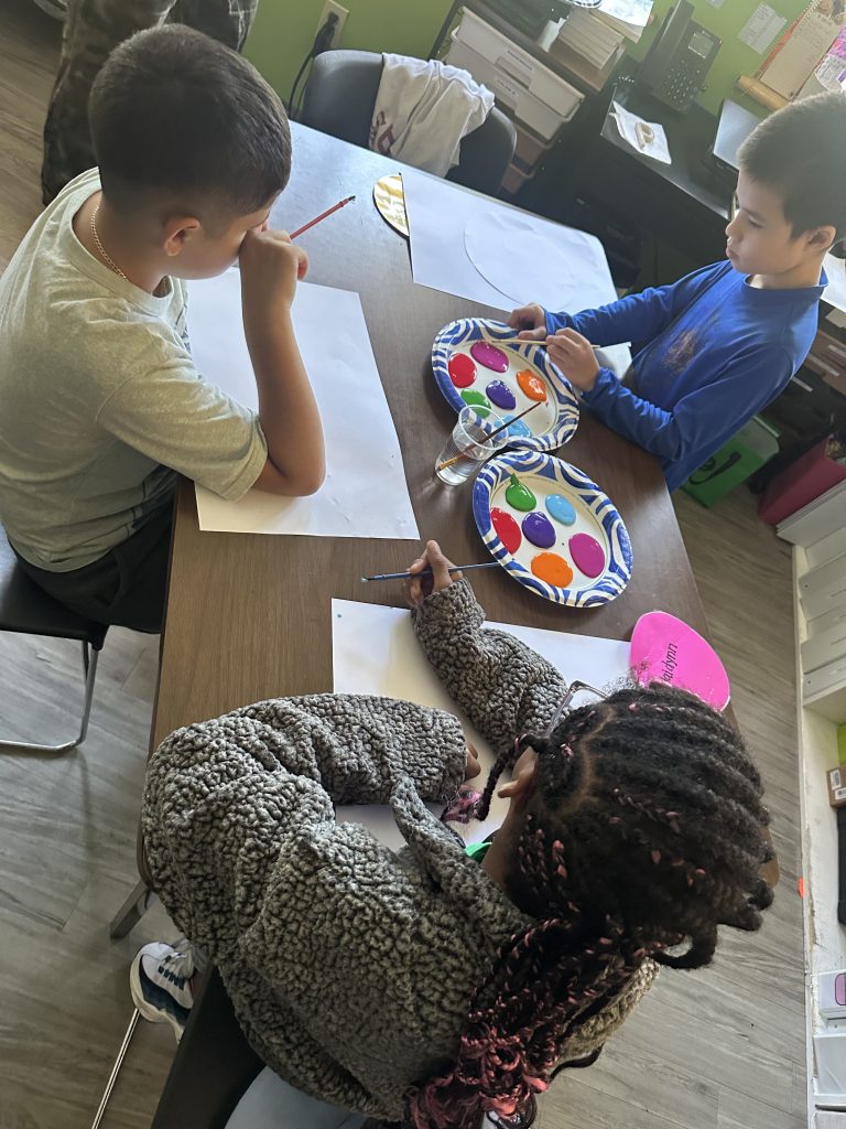 Students work with paint and brushes to create individual dot designs at High Road School of Fairfield County.