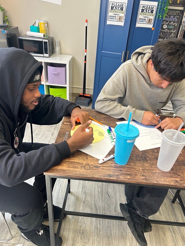 High school students create their own dot designs using markers during International Dot Day.