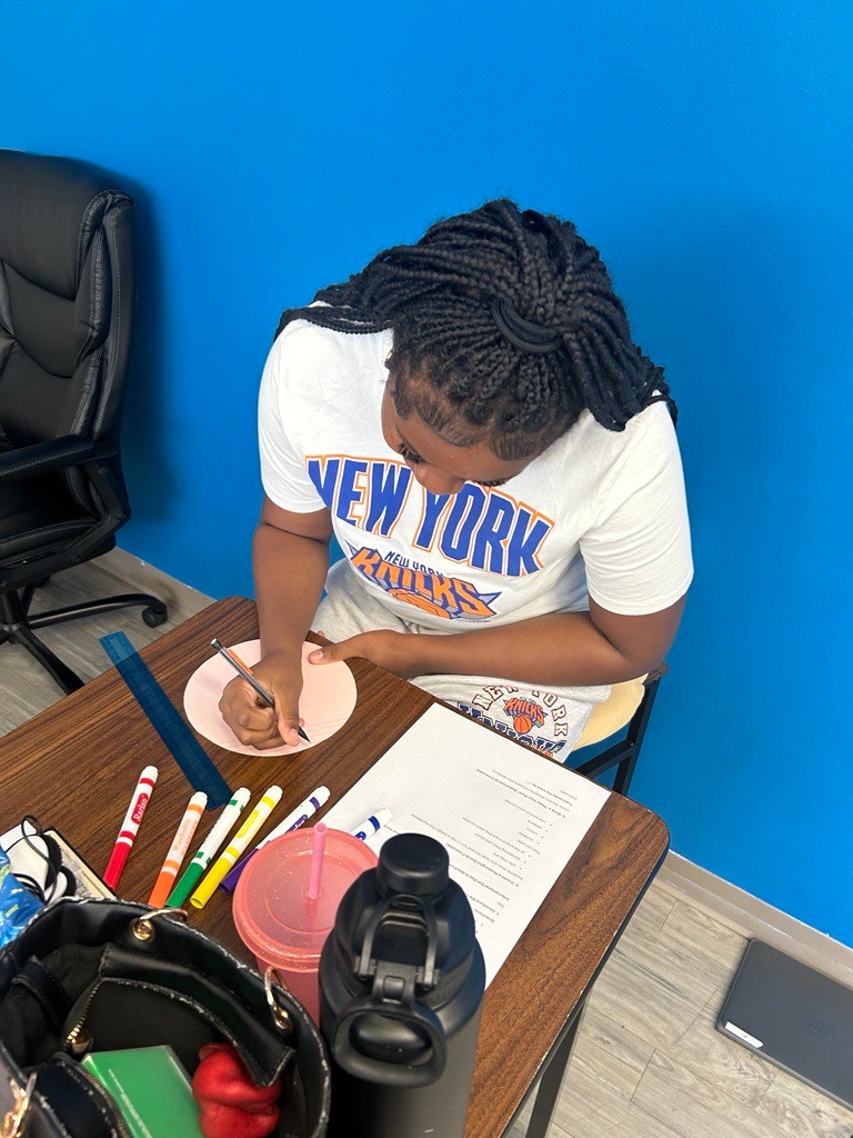 Student draws on a paper circle as part of an International Dot Day classroom activity.