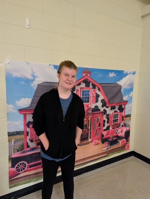 Staff member poses by Dolly Day decorations at Northwest Center for Autism at High Road School