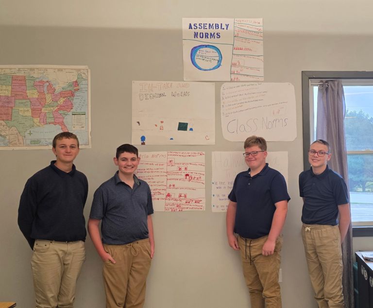 Students standing beside classroom norm posters created during back-to-school activities