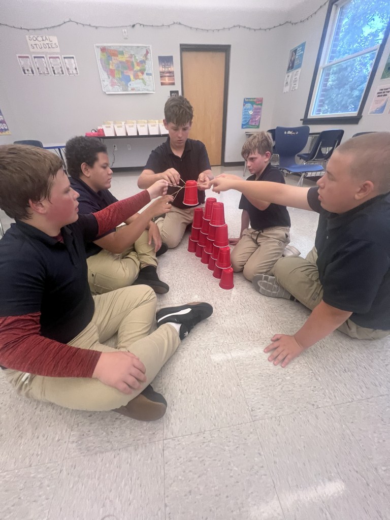 High Road students working together on a cup-stacking team-building challenge