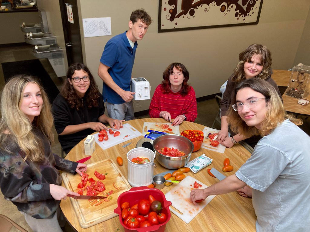 Alumnos de la NewHope Academy preparando tomates cultivados en el huerto de la escuela