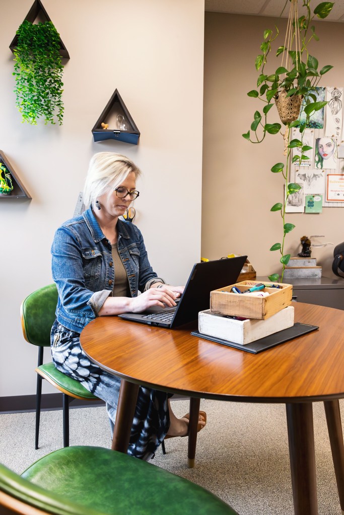 Meaghan Torrence, Associate Director at NewHope Academy, working on a laptop in her office
