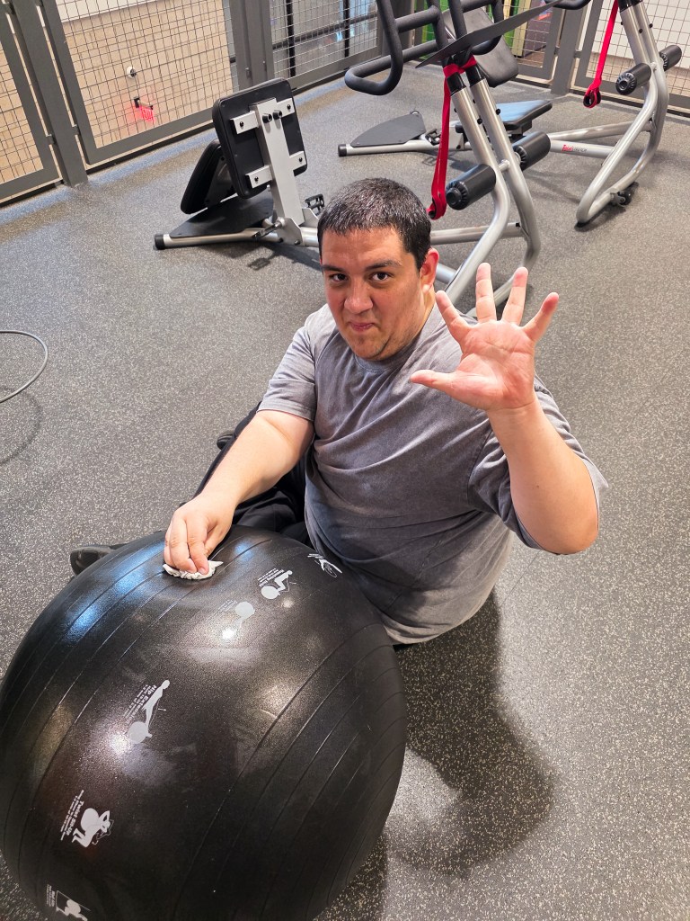 Student cleans exercise equipment while practicing workplace skills through work-based learning.