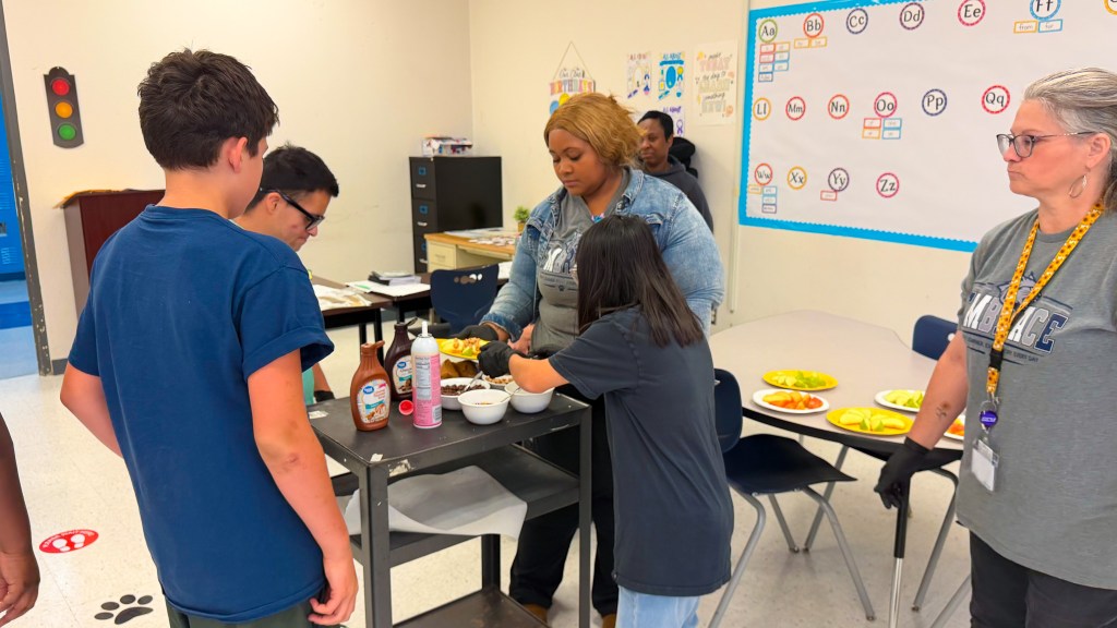 Students and staff from Sierra School at Krum and EMBRACE prepare apples and toppings during a classroom apple bar activity.