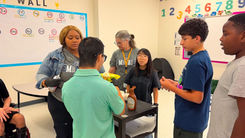 Students and staff from Sierra School at Krum and EMBRACE prepare apples and toppings during a classroom apple bar activity.