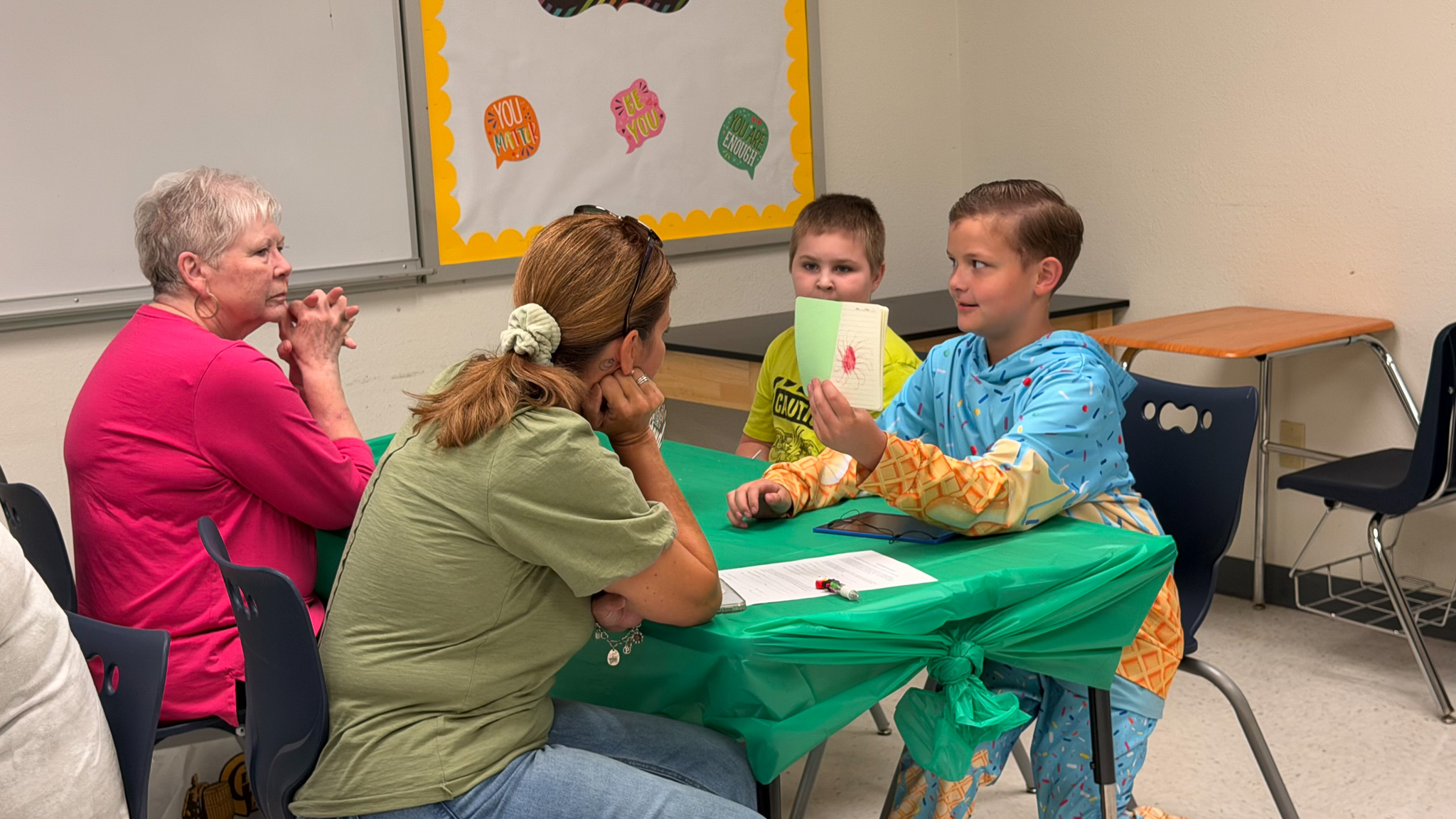 Un alumno de la Sierra School of Krum comparte sus trabajos escolares con sus familiares durante el desayuno con los abuelos.