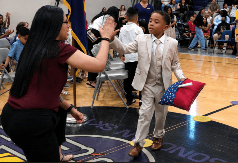Student and staff member share a high-five during a Sierra School at Pendergast school celebration