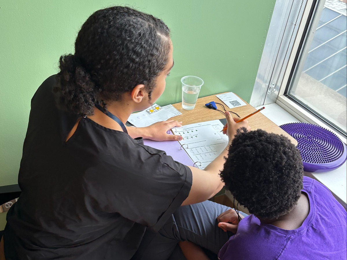 A High Road School of Delaware student receives one-on-one academic support from a staff member in the Bloom classroom.