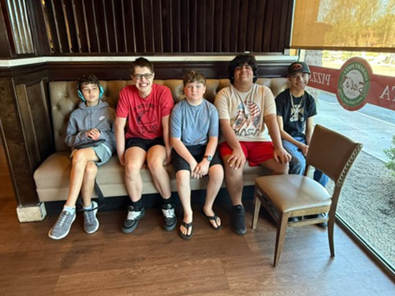 Five Sierra School of Gilbert students sit together inside Sal's Gilbert Pizza during a community workplace learning visit.