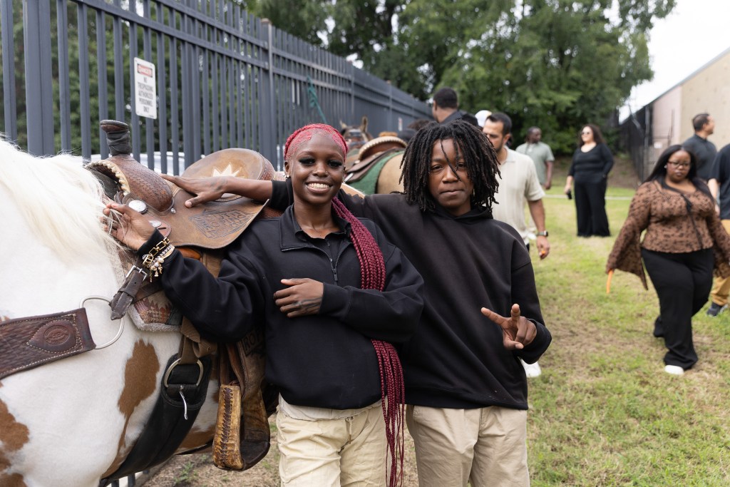 1. Dos alumnos de Achieve Academy East posan junto a un caballo durante la visita de los Concrete Cowboys a Filadelfia.