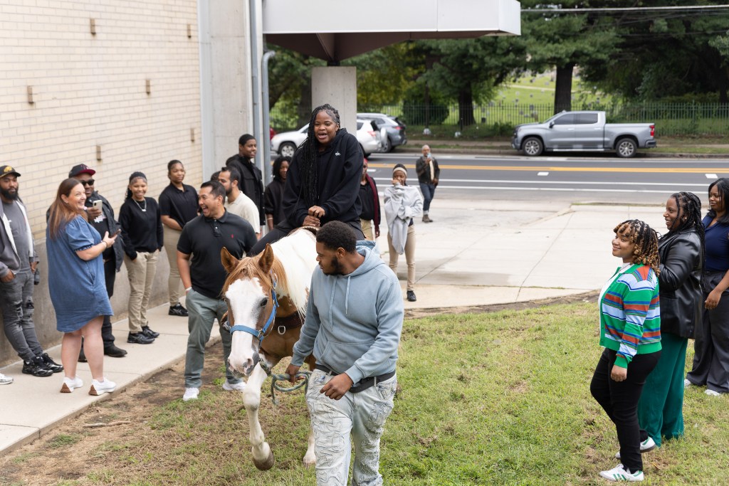 Un alumno de la Achieve Academy East monta a caballo mientras sus compañeros y el personal observan durante la visita de los Concrete Cowboys.
