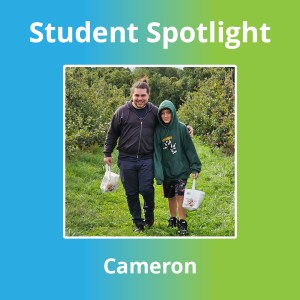 Cameron B., alumno de la High Road School de Wallingford, posa junto a un miembro del personal durante una excursión a un huerto de manzanos.