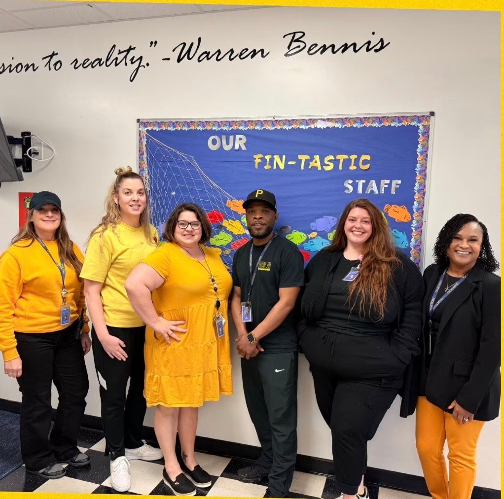 Carl Blackmon stands with High Road School of Santa Rosa staff members in front of a staff display.