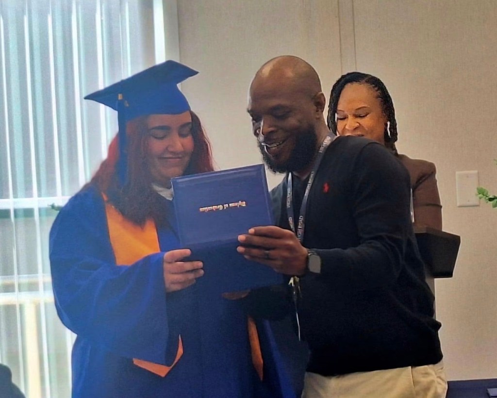 1. Carl Blackmon presents a diploma to a High Road School of Santa Rosa graduate during a graduation ceremony.