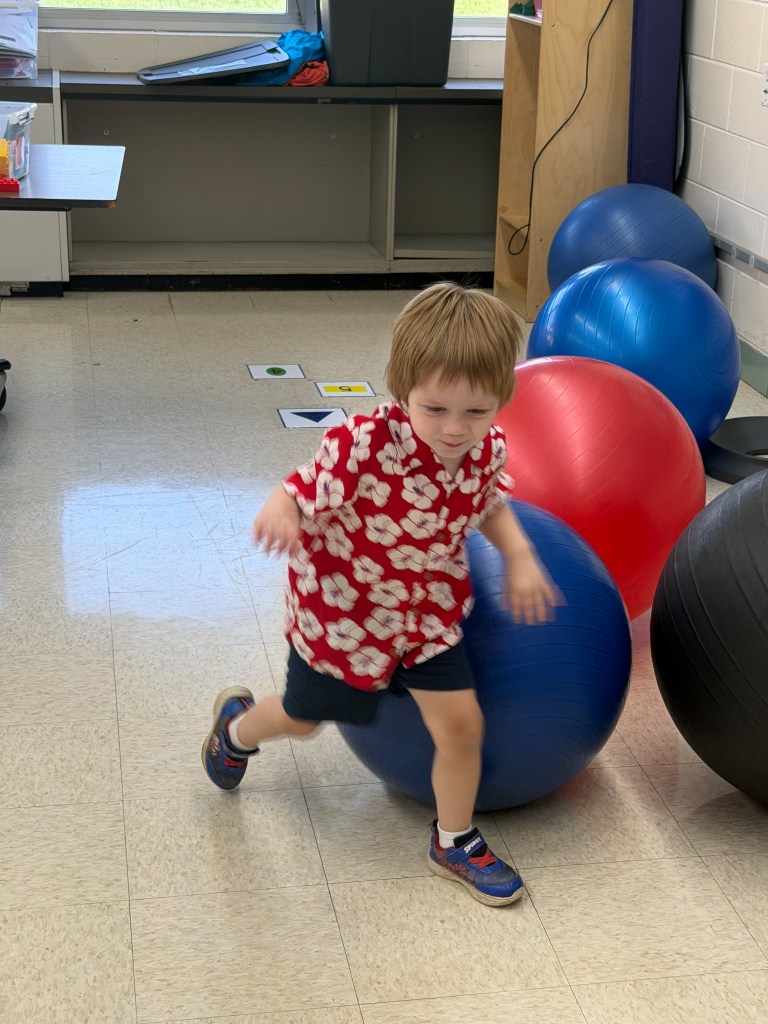 Young student participating in a movement activity with a therapy ball in the early childhood classroom.