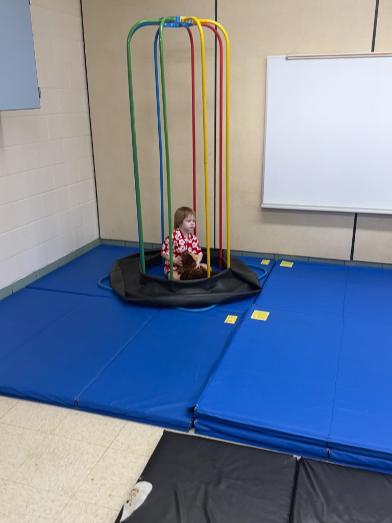 1. Young student using sensory equipment on padded mats in the High Road early childhood special education classroom.