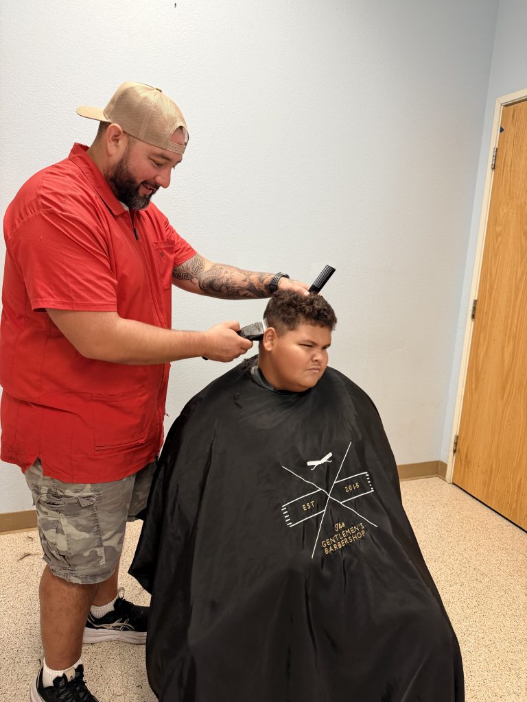 Barber giving a Lattice Educational Services student a Picture Day haircut on campus.