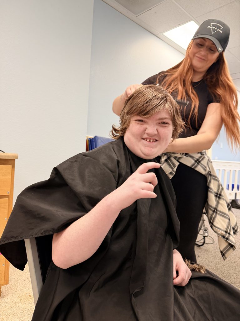 1. Lattice Educational Services student smiling during an on-campus Picture Day haircut.