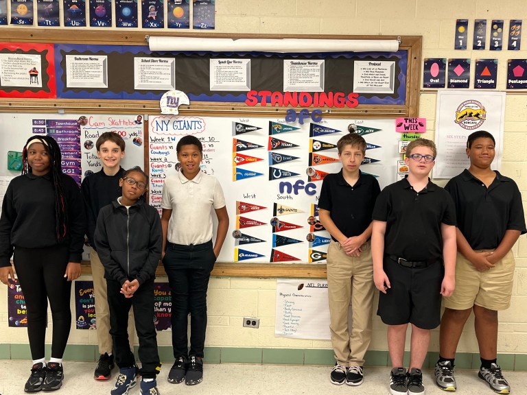 High Road School of Belvidere students standing beside an NFL standings board used for football-themed classroom activities.