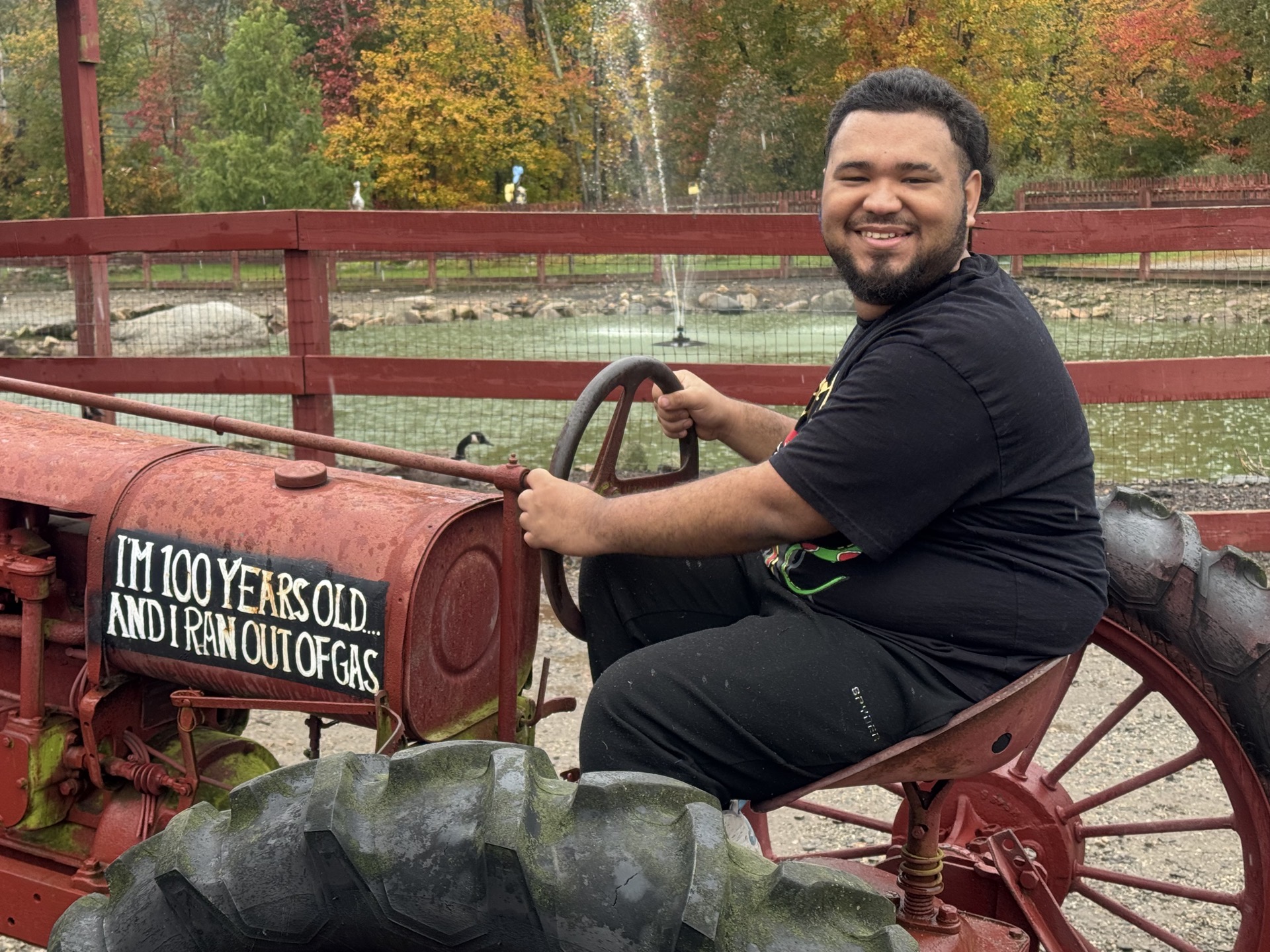 Un alumno de la High Road School del condado de Fairfield sonríe sentado en un tractor rojo de época durante una excursión de otoño a la granja de Silverman.