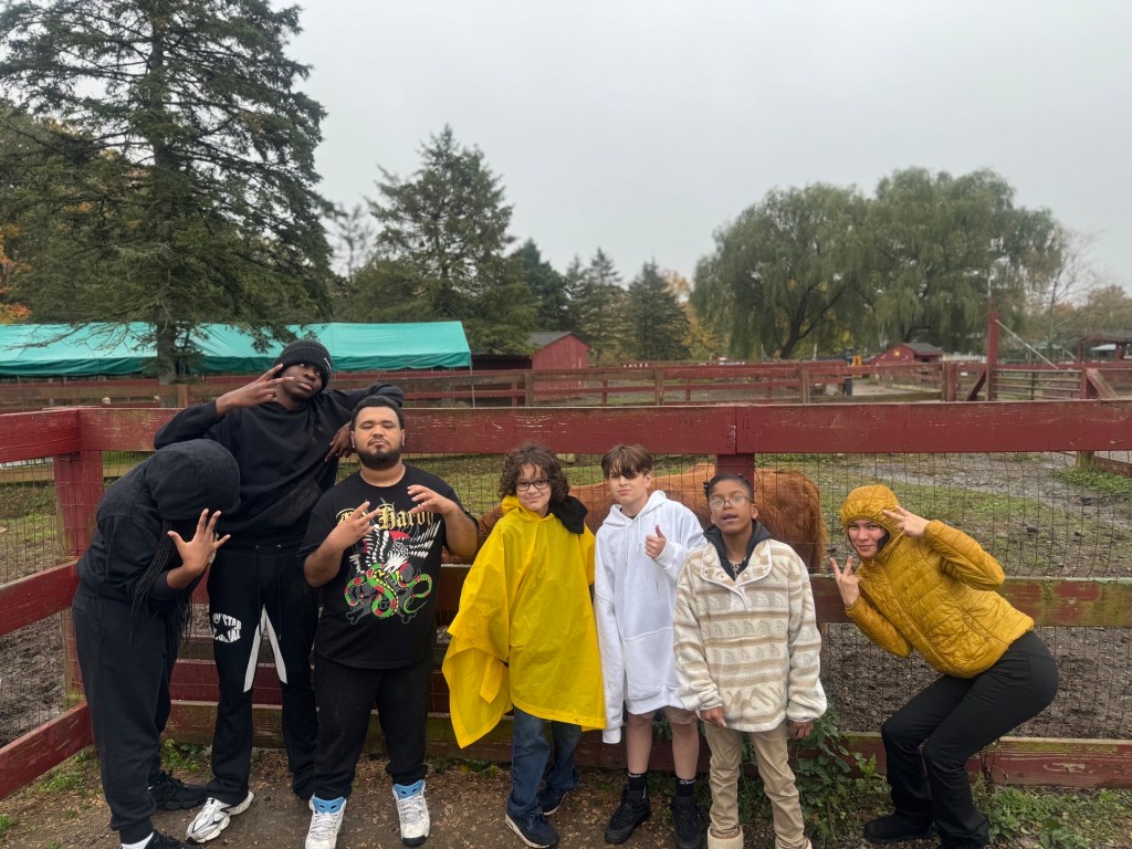 Los alumnos de la High Road School del condado de Fairfield posan juntos para una foto de grupo junto a un recinto de animales durante su excursión de otoño.