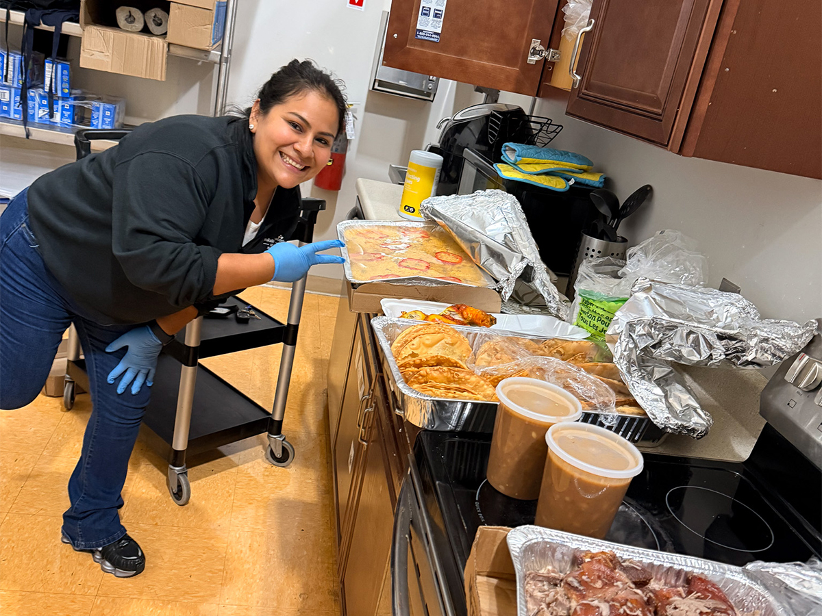 Un miembro del personal de la High Road School de Hartford junto a la comida preparada para la celebración del Mes de la Herencia Hispana.