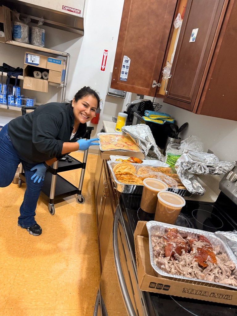 Un miembro del personal de la High Road School de Hartford junto a la comida preparada para la celebración del Mes de la Herencia Hispana.