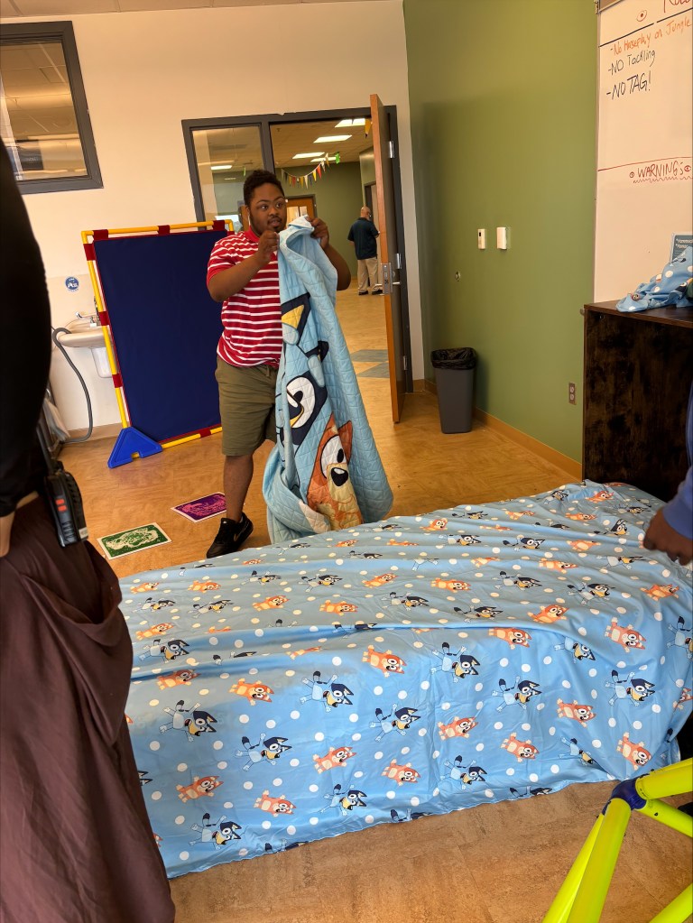A student holds bedding while practicing daily living skills in the Bloom classroom at High Road School of Delaware.