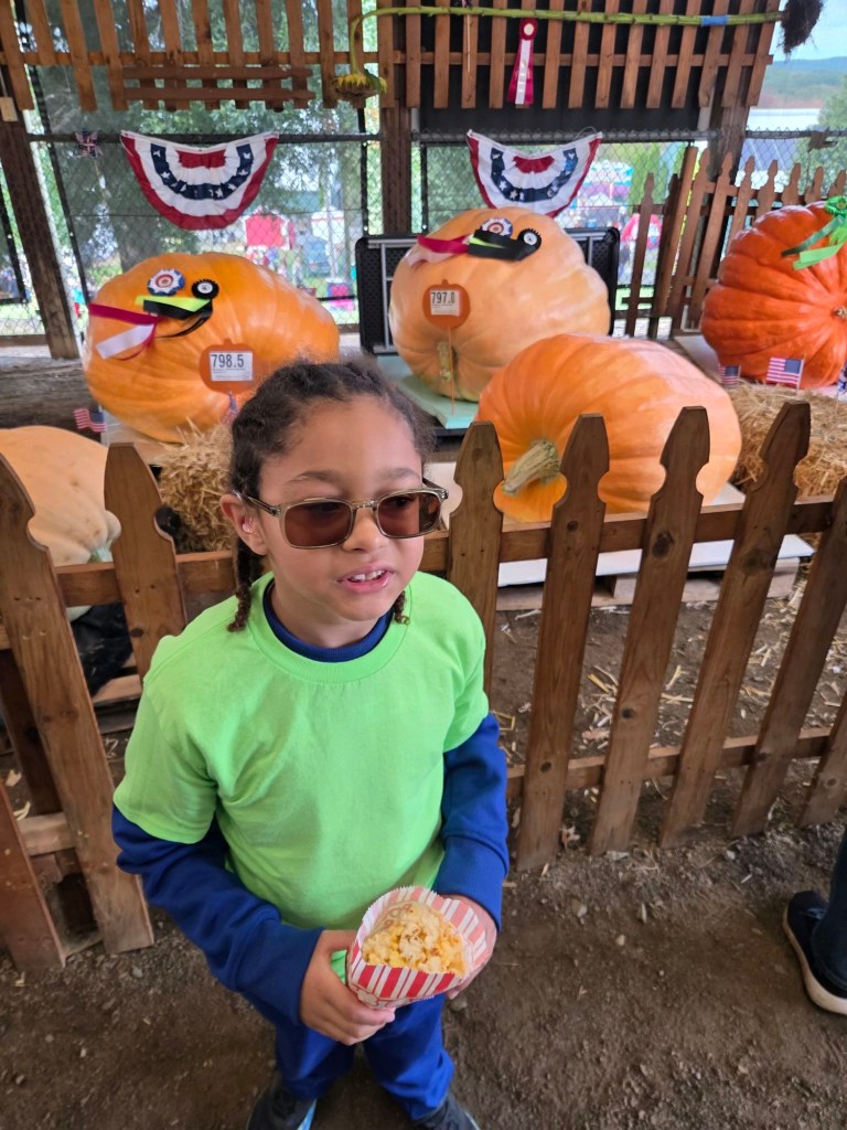 Jose standing near large pumpkins during a class trip to the Durham Fair.