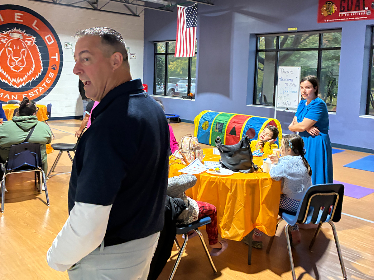 Las familias y el personal se reúnen en el gimnasio durante la jornada de puertas abiertas de la escuela High Road de Hoffman Estates.
