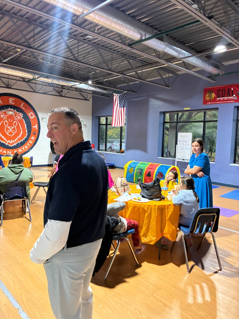Las familias y el personal se reúnen en el gimnasio durante la jornada de puertas abiertas de la escuela High Road de Hoffman Estates.