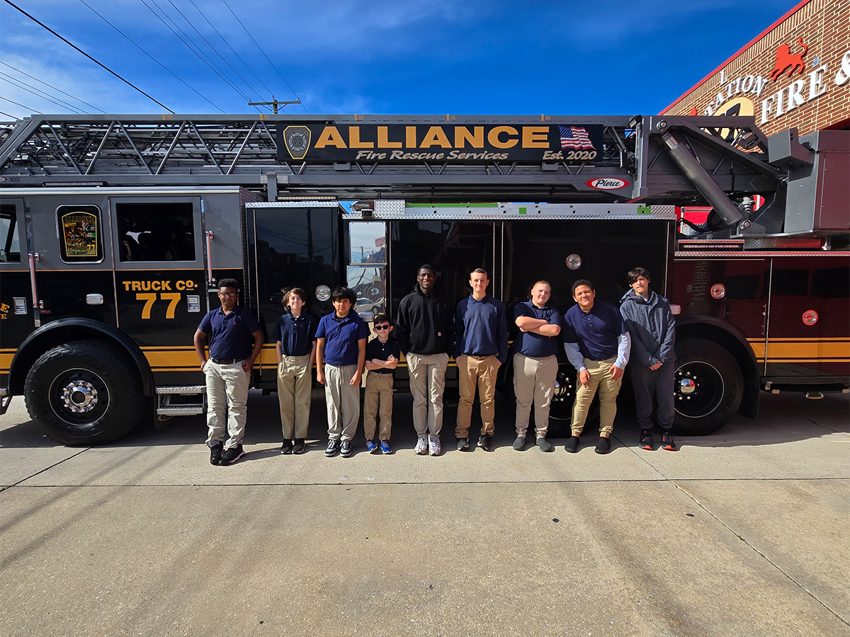 Los alumnos de la High Road School de York posan juntos junto a un camión con escalera del cuerpo de bomberos Alliance Fire Rescue.